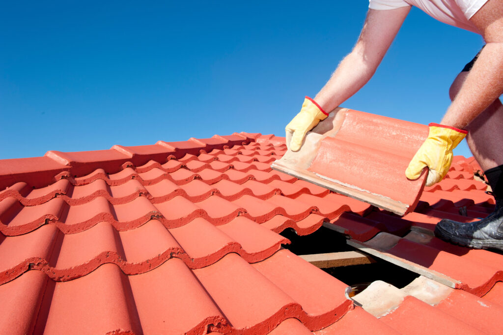 Roofer laying new tiles for roof installation